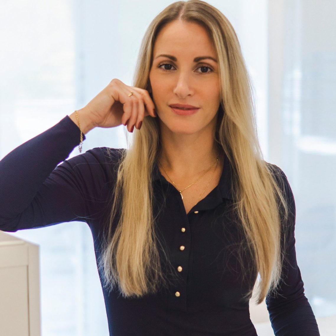 Eine Frau mit langen, blonden Haaren in einem eleganten, dunklen Oberteil.