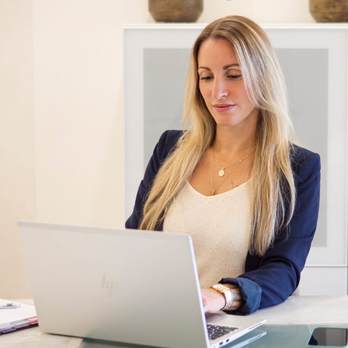 Eine Frau mit langen Haaren arbeitet konzentriert am Laptop.